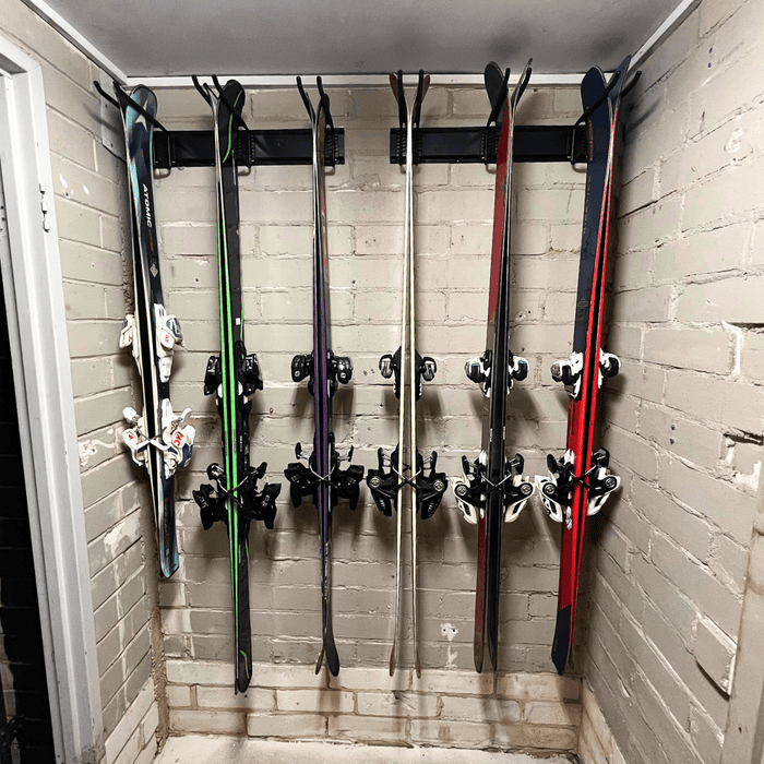 ULTRARACK rails mounted into a brick garage wall holding six pairs of skis vertically